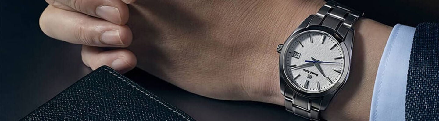 Close-up of a person&rsquo;s wrist wearing a white dial and steel bracelet Grand Seiko watch 